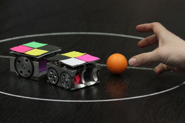 Roboty sleduje kamera a předává informace počítači. Ten roboty řídí.