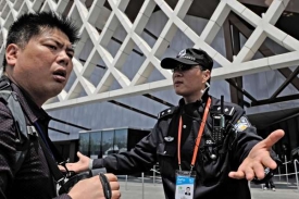 Vraťte se do fronty, žádá policista čínského návštěvníka.