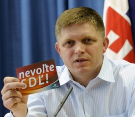 Robert Fico ukazuje samolepky, které mají poškodit jeho stranu.