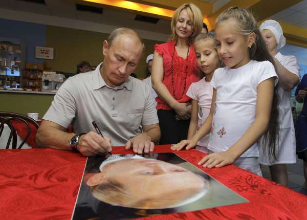 Putin podepisuje dětem svůj plakát.