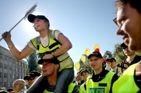 Někteří z demonstrujících mají policejní žluté reflexní vesty a jiní třeba hasičskou houkačku. 