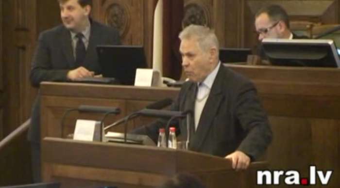 Lácis hovoří v lotyšském parlamentu.
