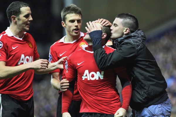Wayna Rooneyho (uprostřed) líbá fanoušek United, který vběhl na hřiště.