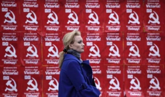 Žena v Kišiněvě kráčí podél volebních plakátů komunistů.