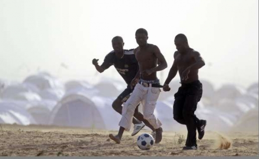 Uprchlíci na libyjsko-tuniské hranici si krátí dlouhou chvíli fotbalem.