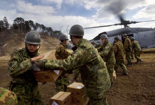 Japonští vojáci distribuují americkým vrtulníkem potraviny do postižené oblasti.