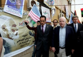Senátor McCain prochází v Benghází kolem plakátu s podobiznou krále Idríse, jehož Kaddáfí kdysi svrhnul.