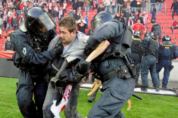 Policisté odvádějí jednoho z agresivních fanoušků.