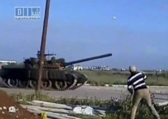 Muž hází kámen na tank v syrském městě Dar'a.