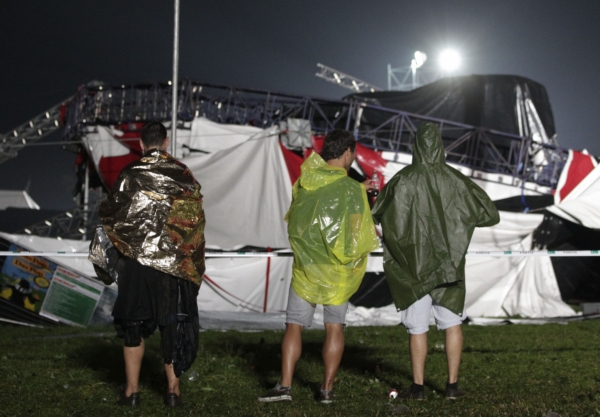 Hudební fanoušci stojí u trosek festivalového stanu.