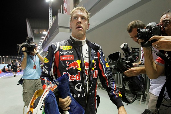 Sebastian Vettel kráčí boxovou uličkou okruhu Marina Bay v Singapuru.