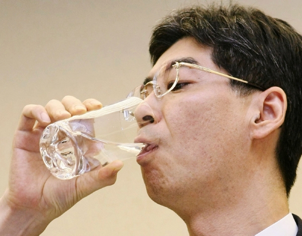 Poslanec Jasuhiro Sonoda hltá vodu odčerpanou z poškozených reaktorů.