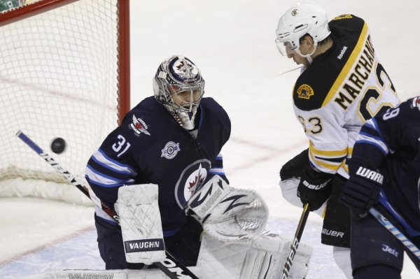 Ondřej Pavelec chytá střelu Brada Marchanta v utkání Winnipegu s Bostonem.