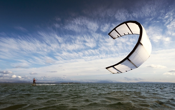 Kitesurfing je jízda po vodní hladině na speciálním prkně a v závěsu za speciálním drakem (ilustrační foto).