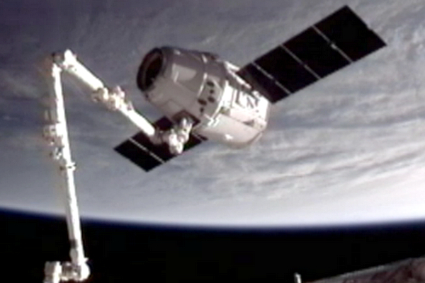 Dragon zachycený robotickým ramenem ISS.