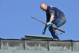 Policista odnáší ze střechy zbraň, kterou střelec použil.