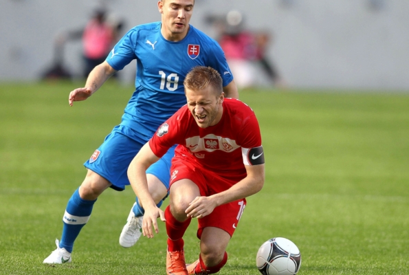 Polák Jakub Blaszczykowski padá v souboji se Slovákem Erikem Jendřiškem.