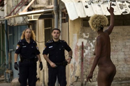 Policisté zadržují nahou súdánskou prostitutku v Tel Avivu. 