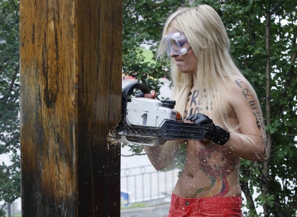 Fešná prsatka z Femen podřezává kříž.