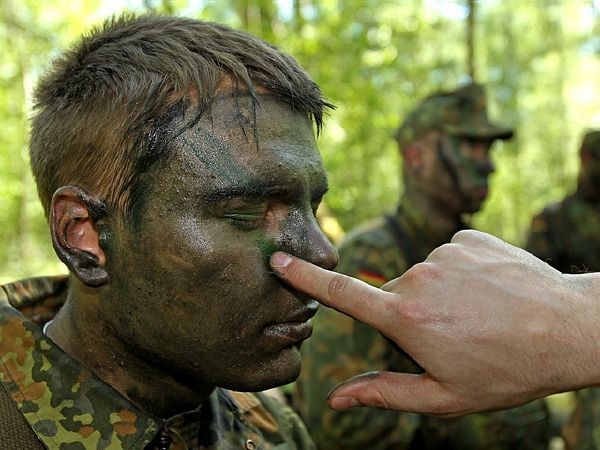 Nováčci německé armády se učí maskování.