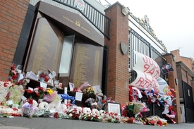 Brána u stadionu Anfield Road je neustále obsypána květinami.