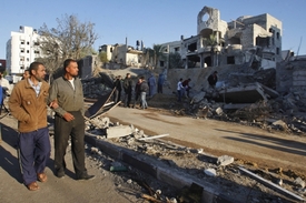 Palestinci procházejí kolem zničeného domu v Gaze.