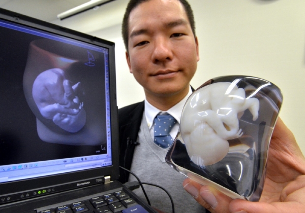 Devět centimetrů vysoký bílý model nenarozeného dítěte uzavřený v průhledném bloku ve tvaru matčina břicha je vyroben na 3D tiskárně.
