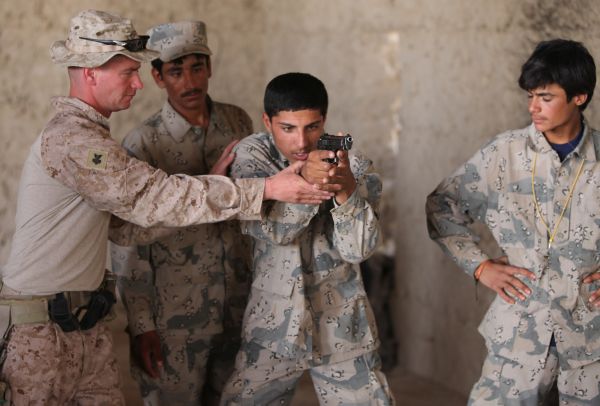 Americký mariňák učí afghánské vojáky střílet s pistolí.
