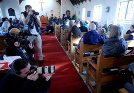 Fotografové hledají dramatické detaily v tvářích účastníků jedné ze smutečních mší v Newtownu.