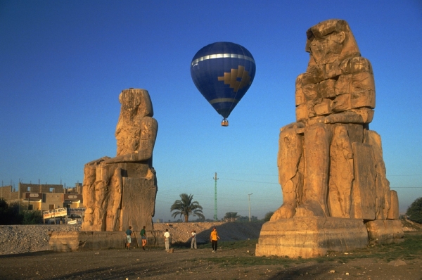 Horkovzdušný balon přelétá Memnonovy kolosy nedaleko Luxoru.