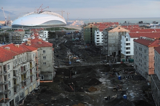 Lidé v Soči si již zvykají na nové součásti města. V pozadí se dokončují práce na Ledový palác, kde se budou odehrávat nejdůležitější zápasy hokejového turnaje.