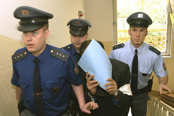 Hámid bin Abdal Sání na cestě k soudu roku 2005 schovává svoji tvář.