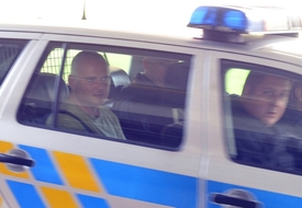 Snímek z 15. června, policisté odvážejí jednoho z obviněných, zřejmě bývalého náměstka ministra zemědělství Romana Bočka (vlevo), kterého soud poslal do vazby.