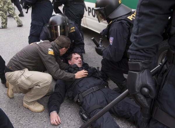 Policisté se snaží zabránit tomu, aby se dav demonstrantů dostal na sídliště, kde žije početná romská komunita. Na snímku je zasažený policista.