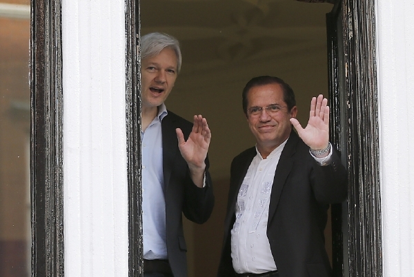 Assange mává z okna ekvádorské ambasády v Londýně, která je trvale obklíčená policisty.