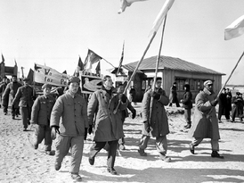 Prokomunističtí američtí váleční zajatci nesou vlajky v čele zástupu amerických, britských a jihokorejských zajatců v Pchanmundžonu