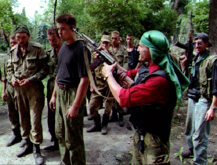 Čečenští rebelové míří zbraní na hlavu zajatého ruského vojáka.