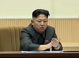 Kim Čong-un seděl zasmušile uprostřed pódia.