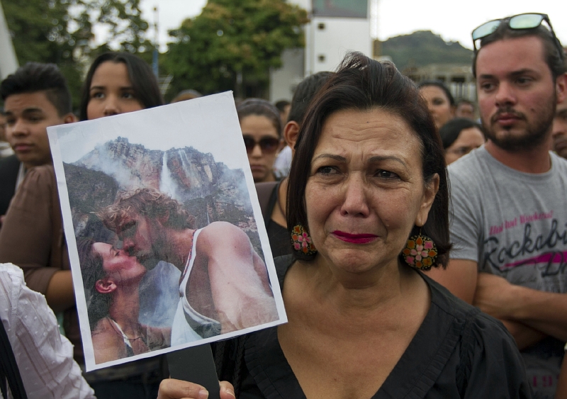 Protest proti násilí. Venezuelská demonstrantka s fotografií zavražděného páru, bývalé miss a jejího exmanžela.
