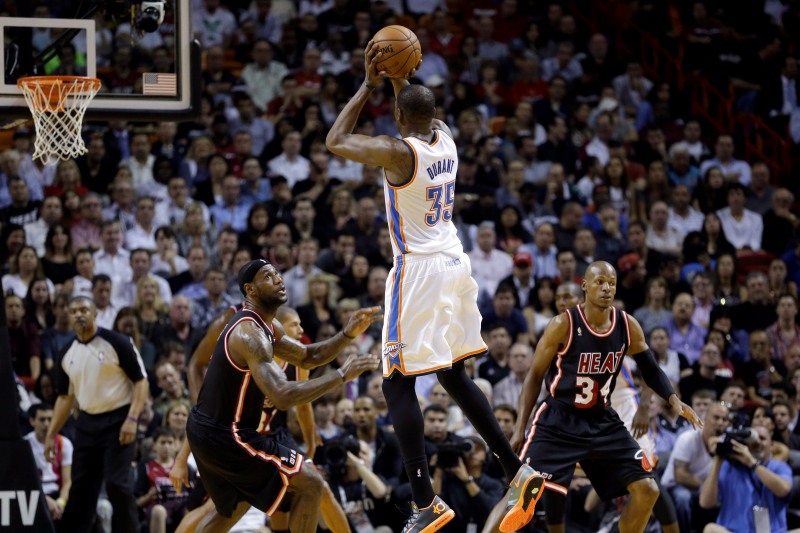 Kevin Durant (v bílém) při střelbě na koš. Vlevo bránící LeBron James