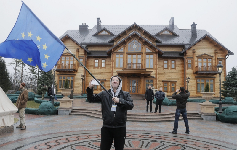 Ukrajinec mává vlajkou EU před residencí sesazeného prezidenta Viktora Janukovyče.