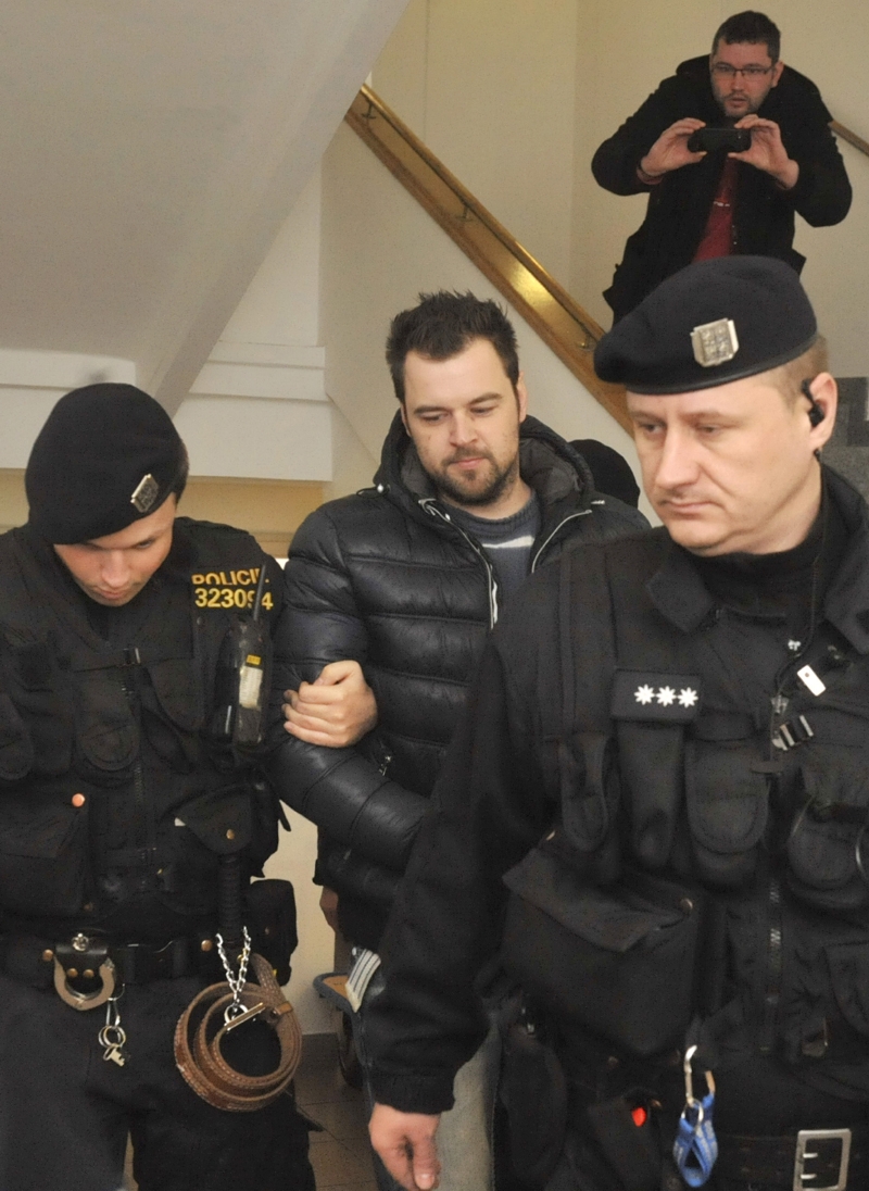 Petra Kramného (uprostřed) odvádějí policisté k výslechu.