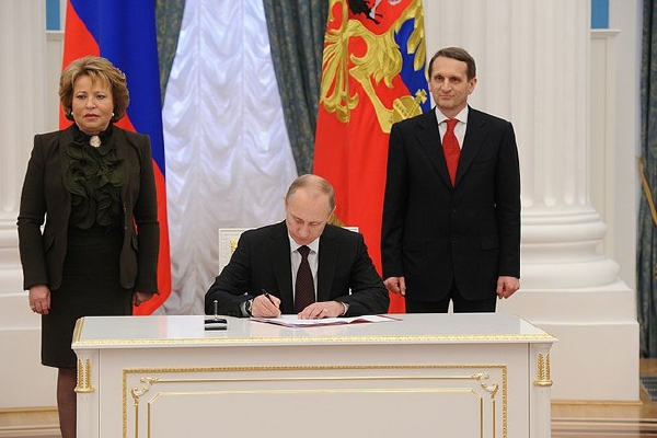 Putin podepisuje zákony o připojení Krymu k Ruské federaci.