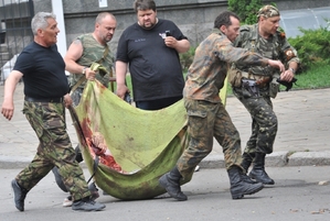 Proruští ozbrojenci odnášejí kusy lidských těl roztrhaných střelami ukrajinské armády.