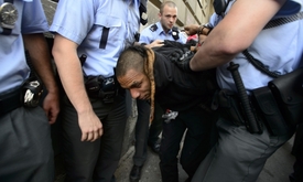 Policisté odvádějí do policejního vozu jednoho z účastníků happeningu.