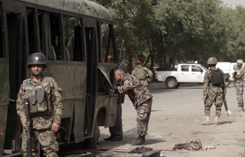 Příslušníci afghánské bezpečnosti prohledávají zničený vojenský autobus po sebevražedném atentátu v Kábulu.