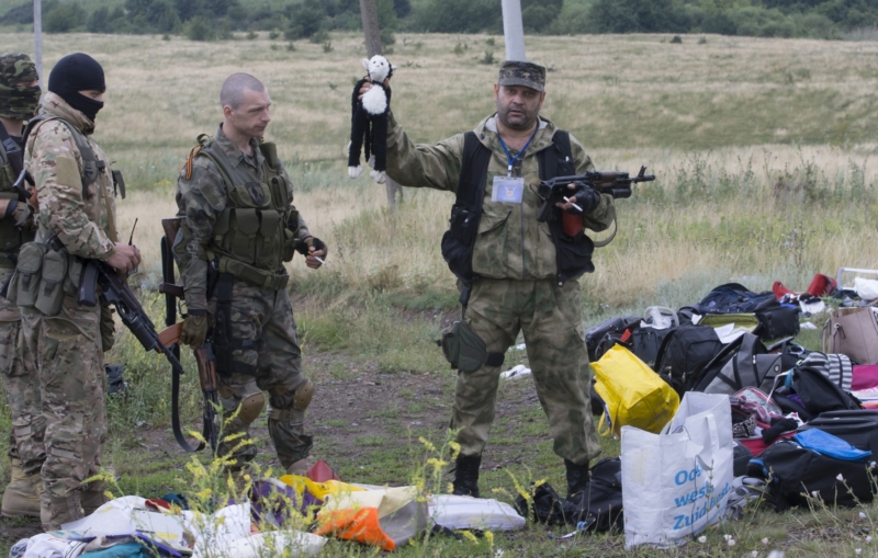 Proruský separatista drží hračku nalezenou mezi sutinami letadla u vesnice Hrabové. Pátek, 18. 7. 2014.