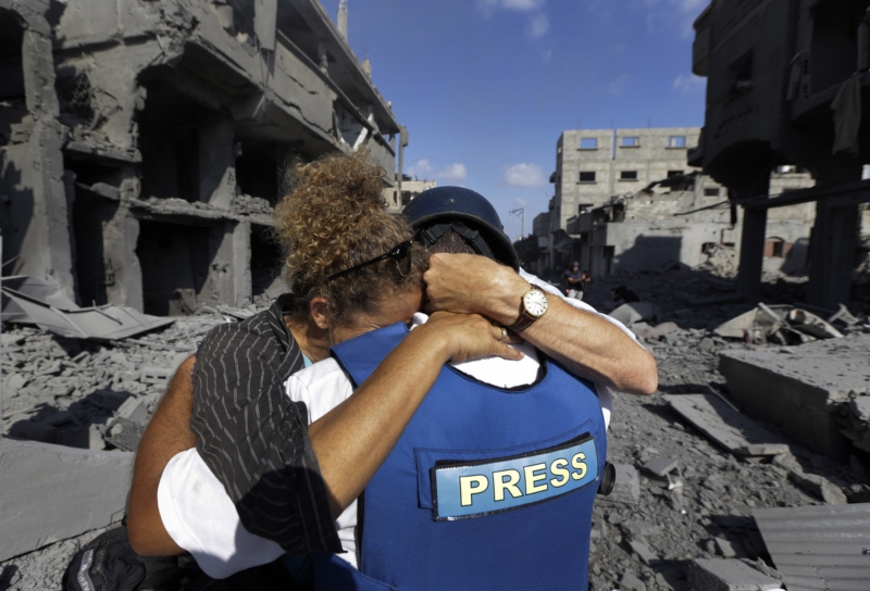Zahraniční novinářka objímá svého palestinského asistenta, který právě zjistil, že izraelské útoky zničily jeho dům.