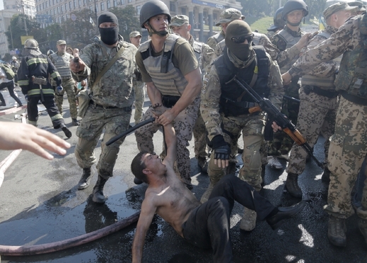 Příslušníci speciálních jednotek zadržují jednoho z demonstrantů.