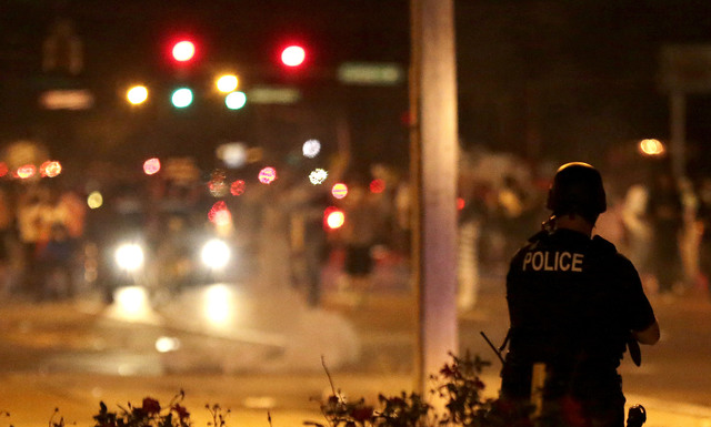 Policista sleduje situaci po použití slzného plynu proti demonstrantům v americkém městě Ferguson.